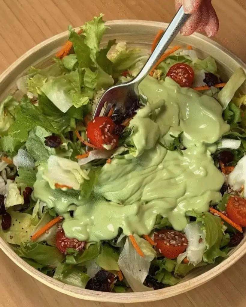 Creamy green dressing over fresh salad with cherry tomatoes and carrots